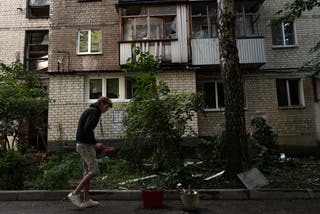 A man removes debris near a damaged residential building following a Russian drone strike in Kharkiv